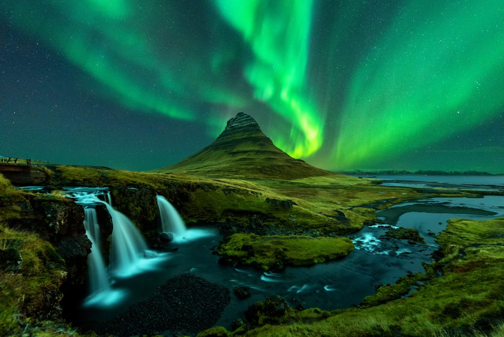 northern lights appear over Mount Kirkjufell with kirkjufellfoss waterfall in Iceland - Blue Ribbon Travel