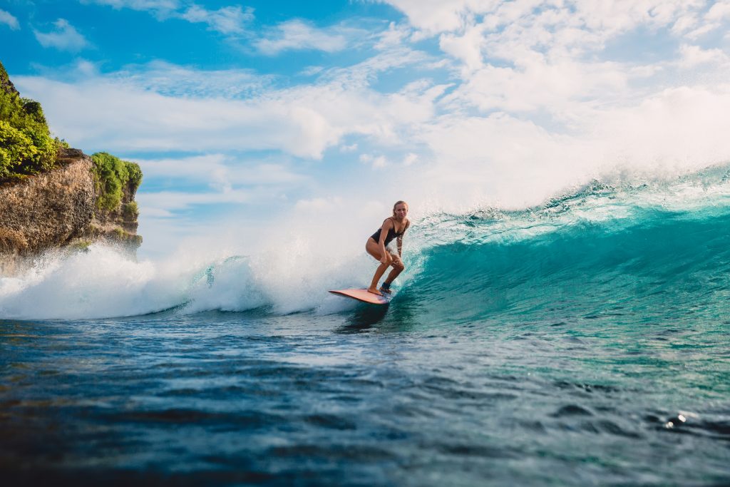 Surf girl on surfboard. Woman in ocean during surfing - Blue Ribbon Travel