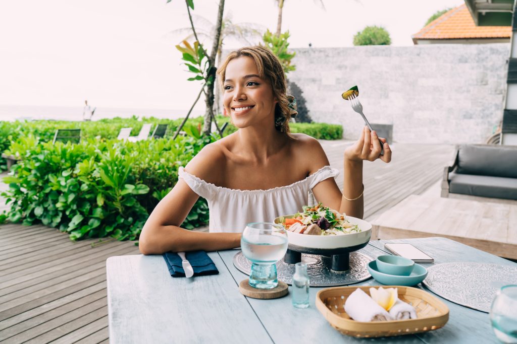 Delighted young woman eating salad - Blue Ribbon Travel